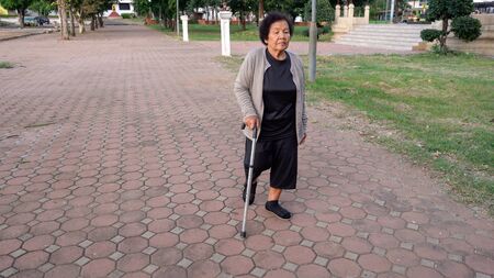 senior woman walking with walking stick in the parkの写真素材
