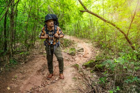 man traveler with backpack looking to the side walking in the natural forest