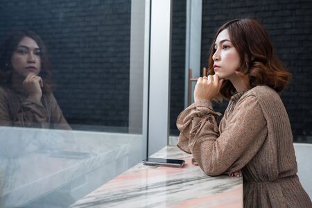 young beautiful woman thinking and looking at windowの写真素材