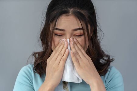 sick young woman is sneezing