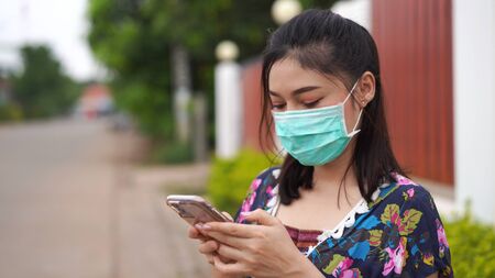 young woman in medical mask(surgical mask) using a smartphone, coronavirus protection