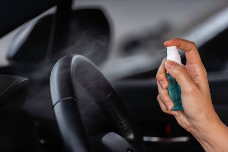 hand spraying alcohol to cleaning car steering wheel for protect from infection of virus and germ Covid-19 coronavirusの写真素材
