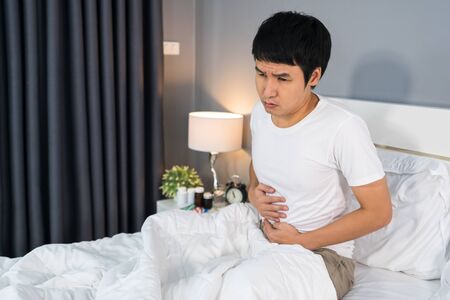 sick man with stomach ache in a bed at homeの写真素材