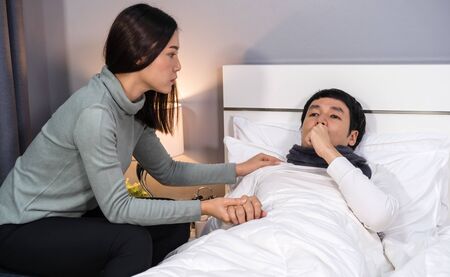 wife visiting and take care her sick husband while he lying on a bed at homeの写真素材