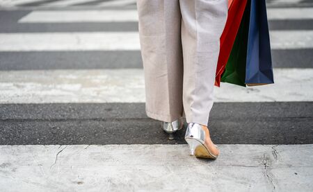woman holding shopping bag walking cross the street in city