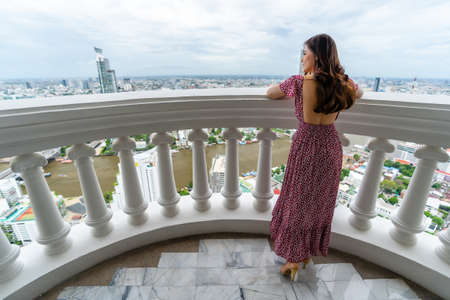 young woman standing on the balcony and looking view of the cityの写真素材