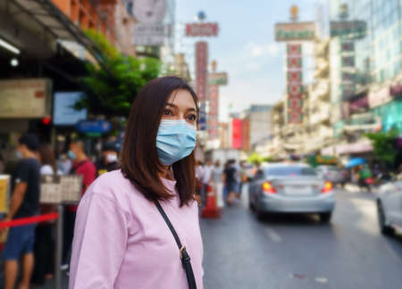 young woman wearing mask at Yaowarat road for prevention COVID-19 virus pandemic in Bangkok's Chinatown.の写真素材