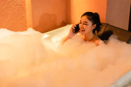 woman talking with mobile phone in the bathtub at the night