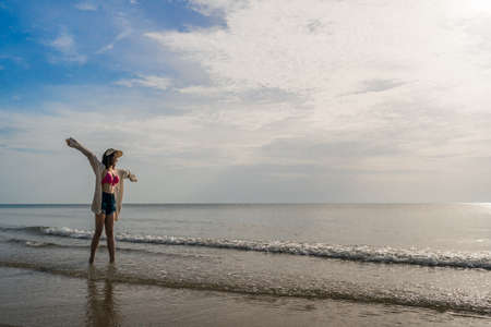 freedom woman in bikini walking with arms raised on the sea beachの写真素材