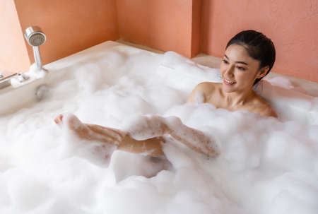 young woman relaxing and takes bubble bath in bathtub with foamの写真素材