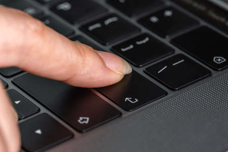 close-up female hand pressing enter button on a laptop keyboardの写真素材