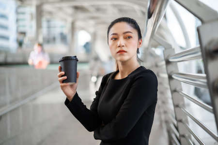 woman holding a cup of coffee and thinking about problem of her business in the city