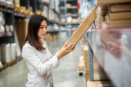 young woman worker checking inventory in the warehouse store