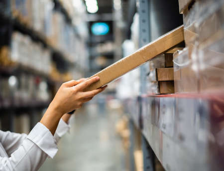 hand is picking up a box in the warehouse storeの写真素材