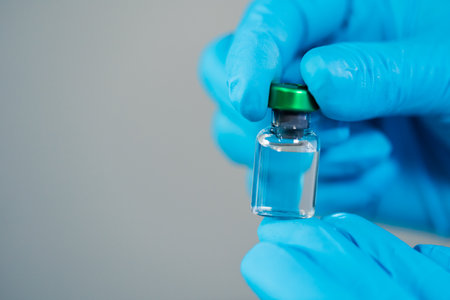hand of doctor holding vaccine bottle for injection medicine