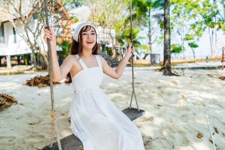 young woman on a wooden swing in the sea beach at Koh MunNork Island, Rayong, Thailandの写真素材