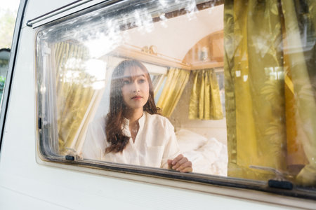 young woman looking view at window of a camper RV van motorhomeの写真素材