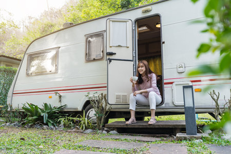 happy young woman drinking coffee at door of a camper RV van motorhomeの写真素材