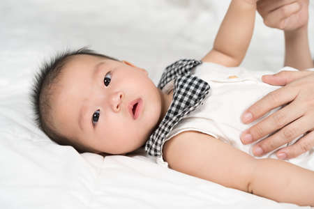 baby with mother hand on a bed at homeの写真素材