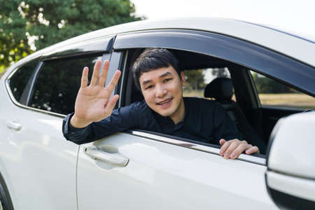 happy man open window of a car and raising his handの写真素材