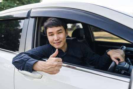young man giving thumb up inside his carの写真素材