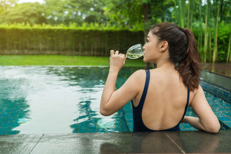 young woman relax in swimming pool and drinking wineの写真素材