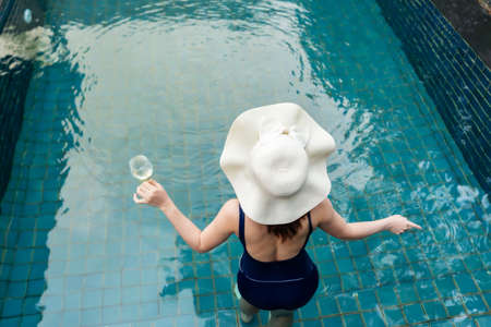 young woman relax in swimming pool and drinking wineの写真素材