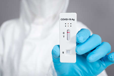 doctor in PPE suit holding Coronavirus(Covid-19) negative test result with Antigen Rapid Test kit (ATK)の写真素材