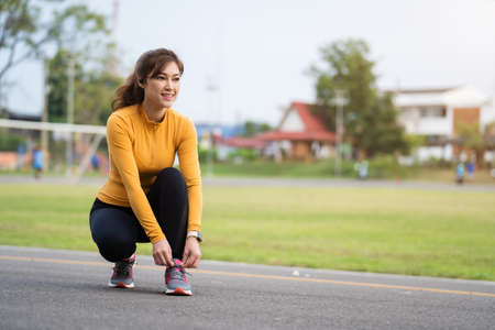 woman tying her running shoes in the parkの写真素材