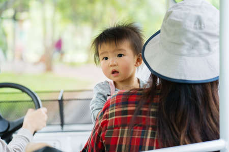 baby with woman sitting in golf cart to travel in the zooの写真素材