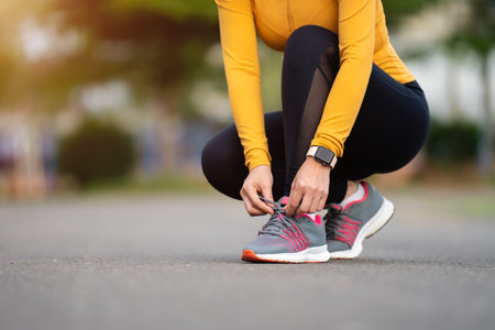 woman tying her running shoes in the park
