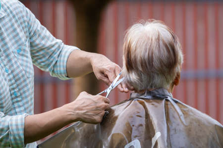 hair stylist cutting senior woman's gray hairの写真素材