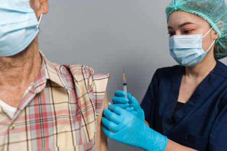 doctor make injection Covid-19 or coronavirus vaccine to senior patient in medical maskの写真素材