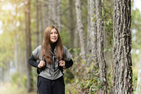 young woman carrying a backpack travel and walking in the forest
