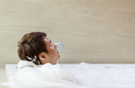 young man relaxing in bathtube with eyes closed in bathroom