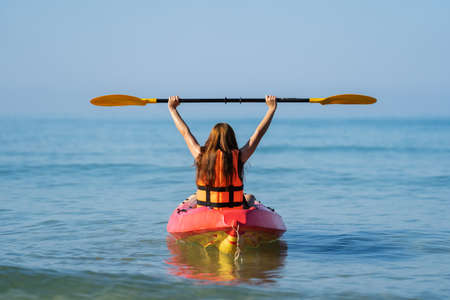 woman in life jacket paddling a kayak boat in the seaの写真素材