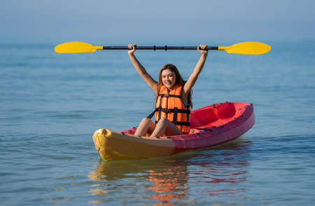 woman in life jacket paddling a kayak boat in the seaの写真素材