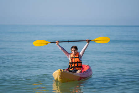 man in life jacket paddling a kayak boat in the seaの写真素材