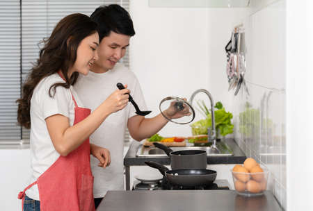 happy young couple cooking and preparing food in the kitchen at home