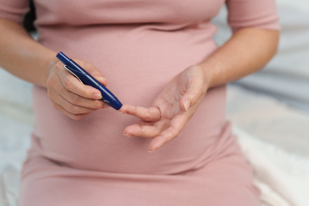 close up of pregnant woman checking blood sugar level by herself at home. gestational diabetes concept.の写真素材