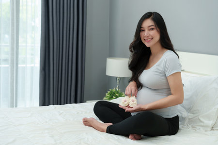 pregnant woman with baby socks or shoes on a bedの写真素材