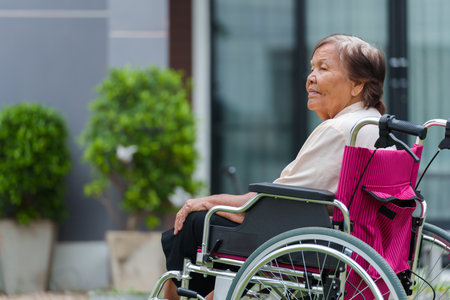 senior woman sitting in wheelchair at outside the houseの写真素材
