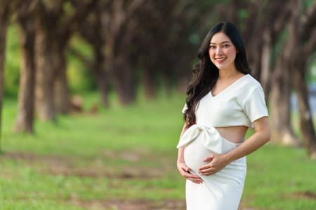 young beautiful pregnant woman stroking her belly in the park