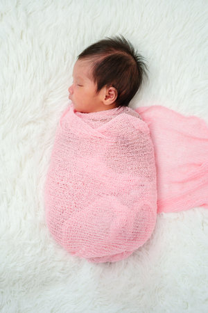 newborn baby sleep in cloth wrap blanket on a bedの写真素材