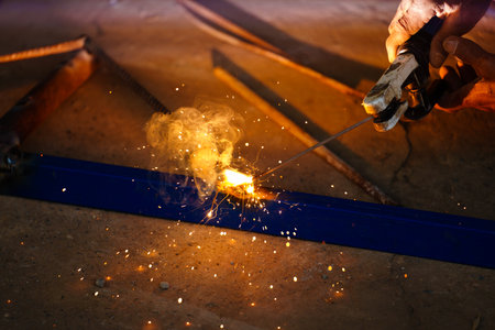 welder working with welding on metal frame with sparking light