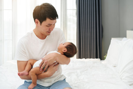 father holding newborn baby on a bedの写真素材