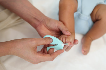 mother cutting newborn baby's foot fingernails with nail scissors.の写真素材