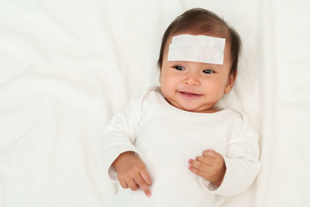 happy sick baby with cool fever jel pad on forehead