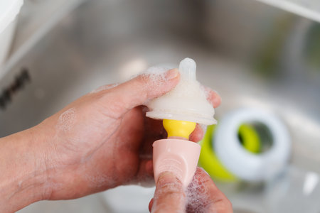 mother hand washing the baby plastic nipple of milk bottleの写真素材