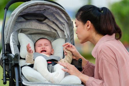 mother consoling her infant baby crying in the strollerの写真素材